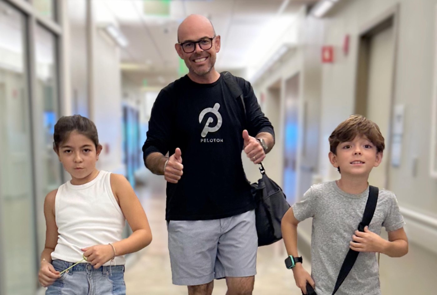John Duffield walking out of the hospital between his two children, giving a thumbs up.