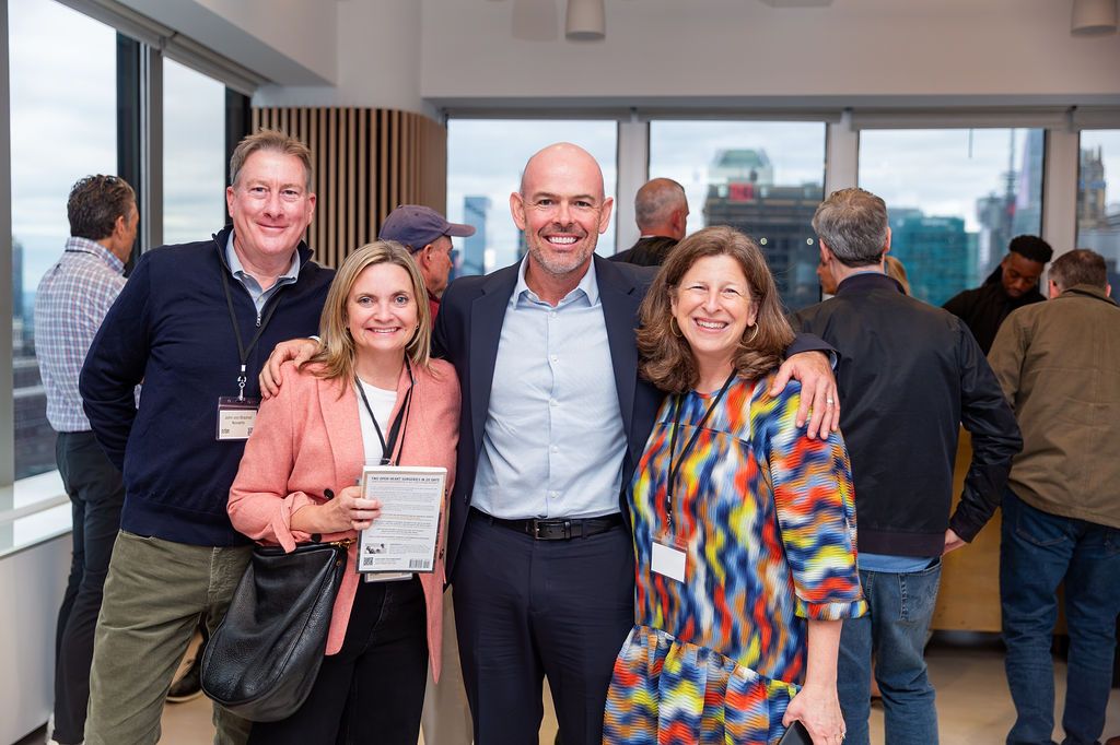 John Duffield with three guests, one holding a copy of The Future Patient, the Manhattan skyline behind them.