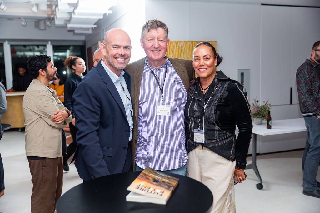 John Duffield with two guests beside a table with a copy of the book on it.
